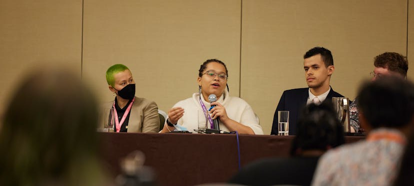 A photo showing three presenters from the 2022 conference speaking.